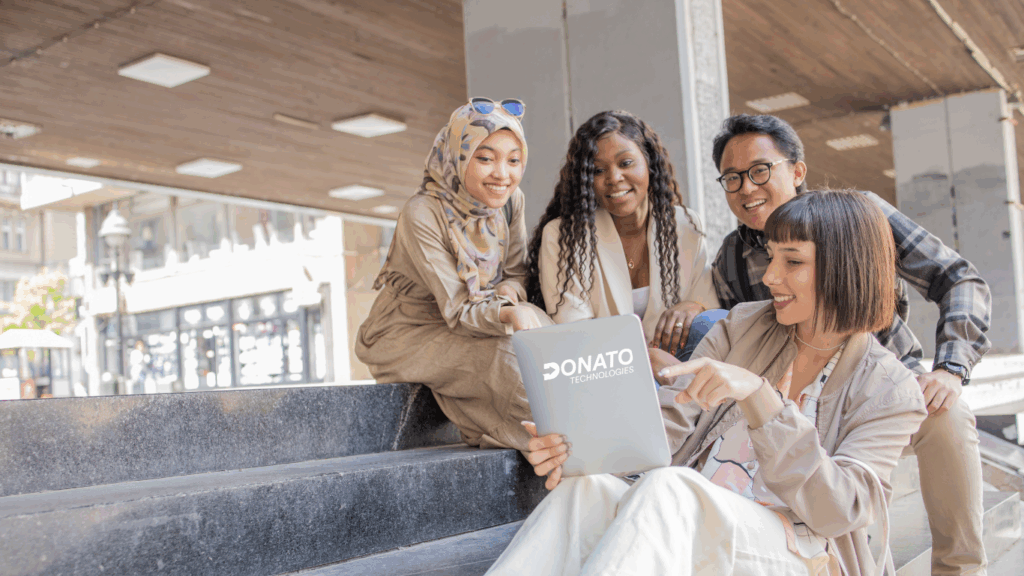 A group of Gen Z professionals sitting on stairs, discussing a tech project and collaborating on ideas for the future workforce.